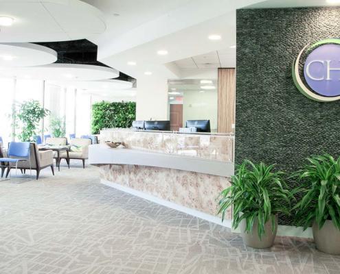 Reception area with high-end natural finishes. Custom marble desk, seating areas and circular ceiling features