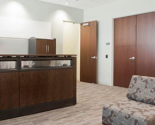 Reception area with dark wood reception desk seating area. Office construction by KasCon